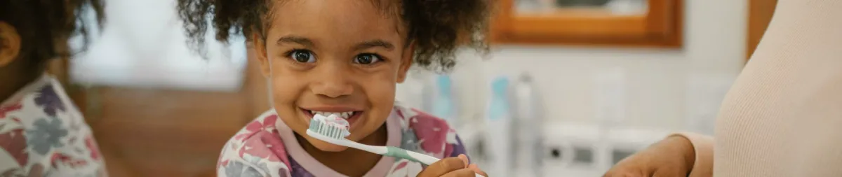 Young child brushing their teeth with fluoride toothpaste, at Bite Squad Dental of NYC